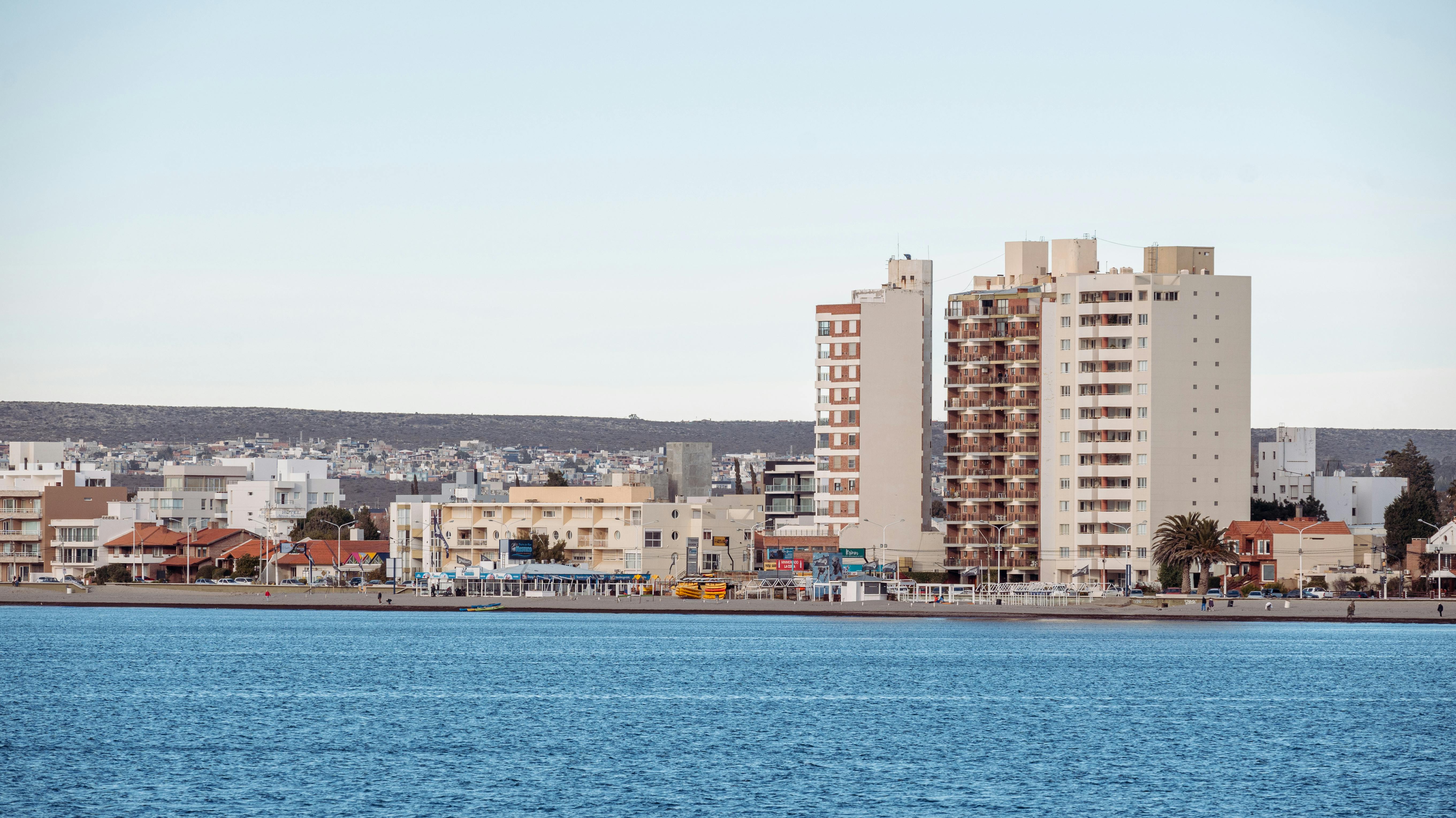 A modern coastal cityscape with tall buildings along a waterfront, showcasing urban development.